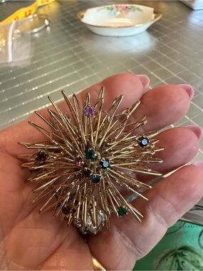 This is a vintage gold-tone atomic starburst brooch